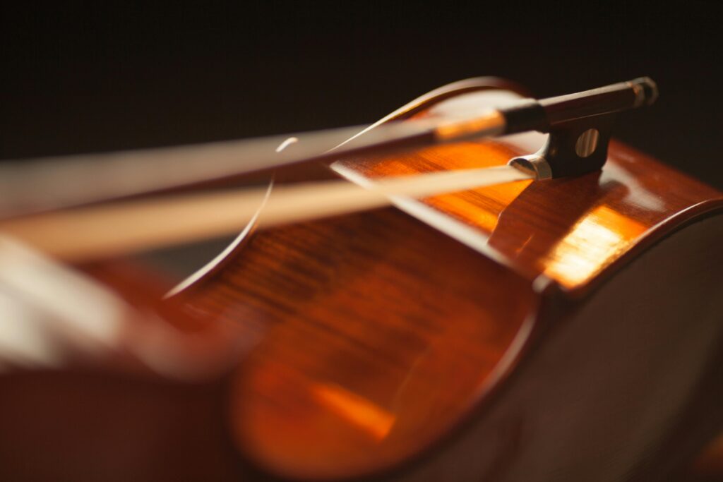 Artistic close-up of a violin with a bow, highlighting warm tones and textures.